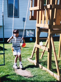 Qasim running across the grass past a wooden play structure.